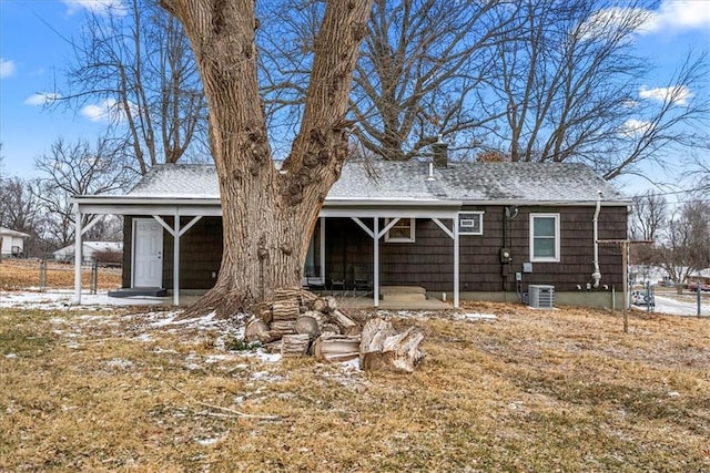 back of property with central AC and roof with shingles