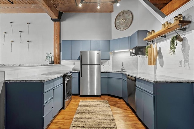 kitchen with blue cabinetry, appliances with stainless steel finishes, open shelves, and a sink