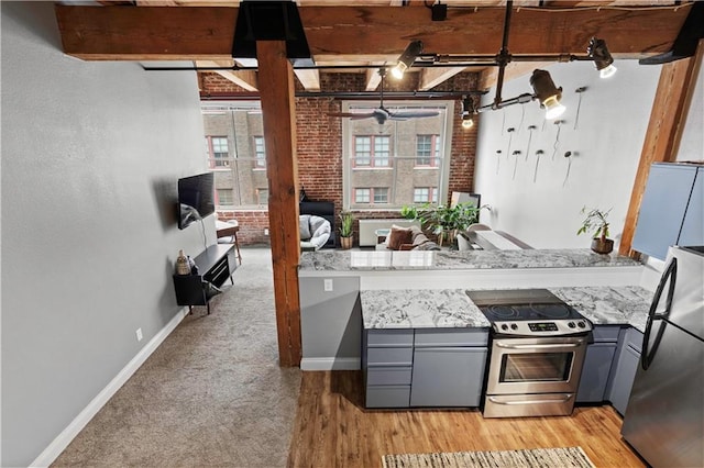 kitchen featuring stainless steel appliances, gray cabinets, beamed ceiling, and brick wall