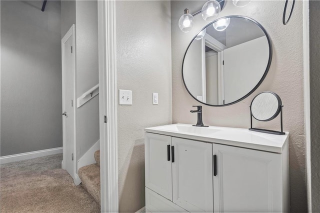 bathroom with a textured wall, vanity, and baseboards