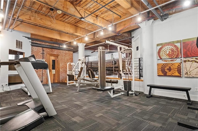 exercise room with brick wall, visible vents, dark carpet, and rail lighting