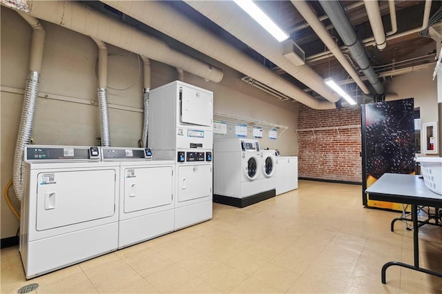 common laundry area with washer and clothes dryer and brick wall