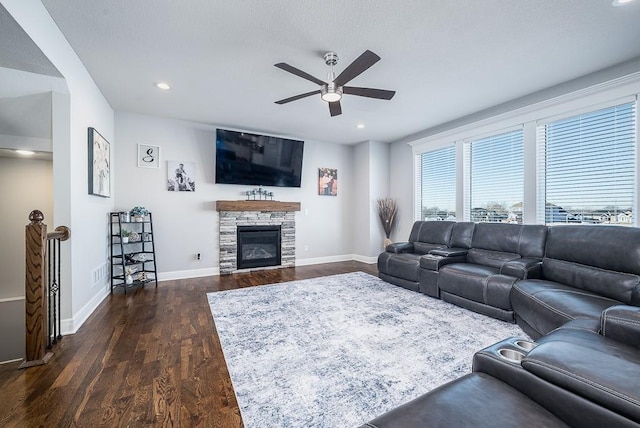 living area with dark wood-style floors, a fireplace, baseboards, and a ceiling fan