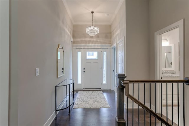 entryway featuring crown molding, dark wood-type flooring, a chandelier, baseboards, and stairs