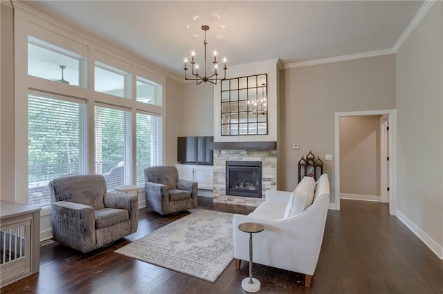 living room featuring a stone fireplace, baseboards, ornamental molding, dark wood-style floors, and an inviting chandelier