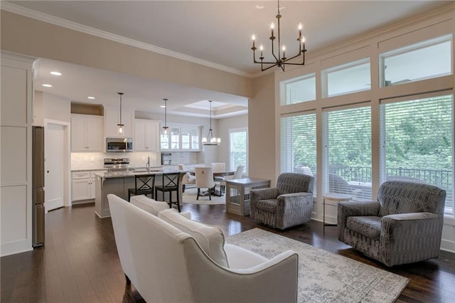 living area with an inviting chandelier, ornamental molding, and dark wood-type flooring