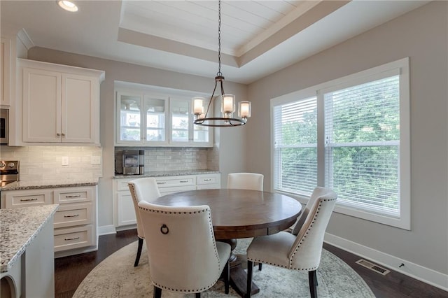 dining room with a raised ceiling, visible vents, baseboards, and a healthy amount of sunlight