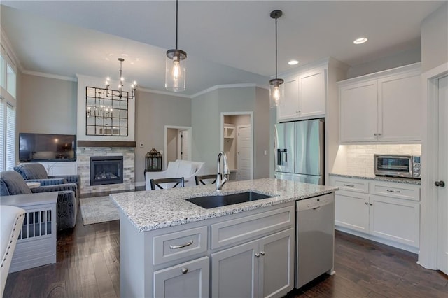 kitchen featuring decorative light fixtures, stainless steel appliances, open floor plan, a kitchen island with sink, and a sink