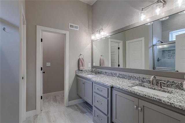 bathroom featuring a stall shower, visible vents, a sink, and double vanity