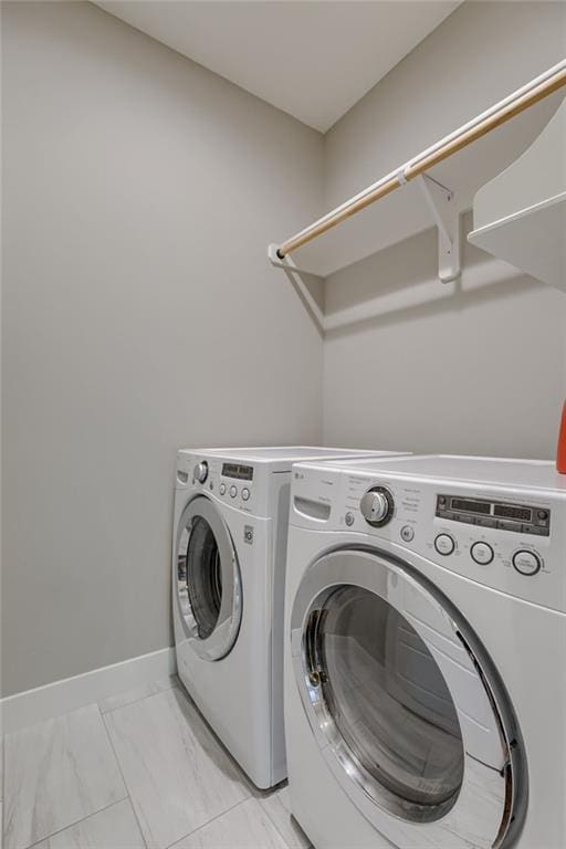 laundry room featuring marble finish floor, laundry area, separate washer and dryer, and baseboards