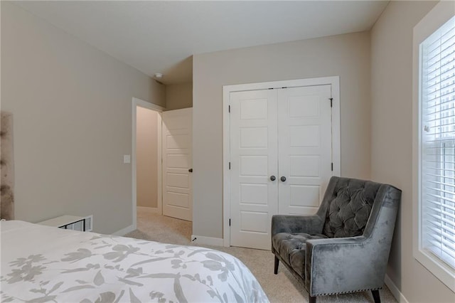 bedroom with light carpet, a closet, and baseboards