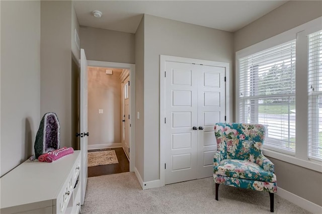 living area featuring light carpet and baseboards