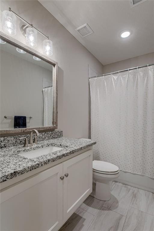 bathroom with toilet, visible vents, and vanity