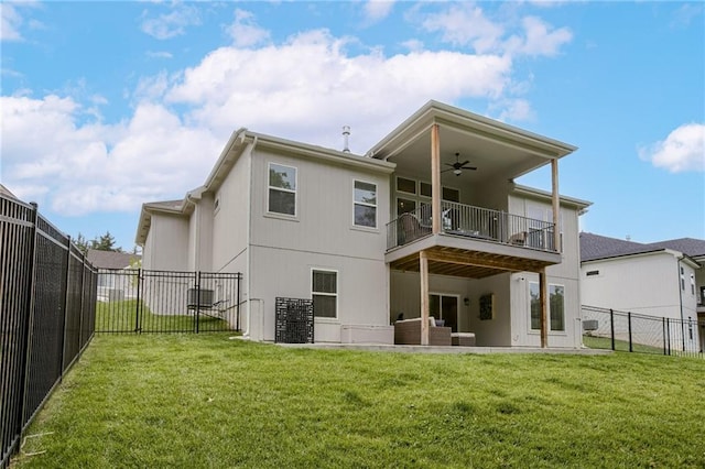 rear view of house with a yard, a fenced backyard, a balcony, and a ceiling fan