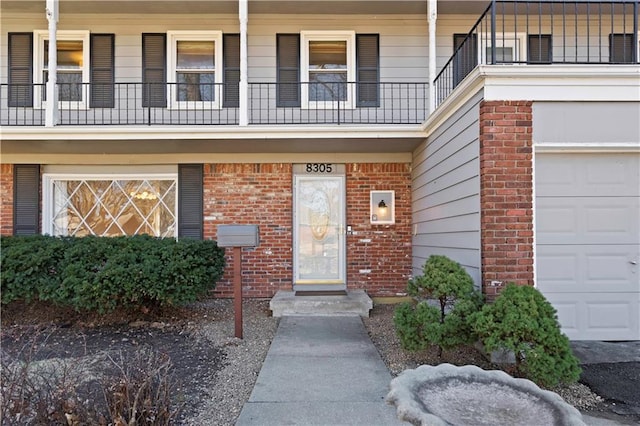 view of exterior entry with a garage and brick siding