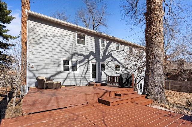 back of property featuring fence, a chimney, and a wooden deck