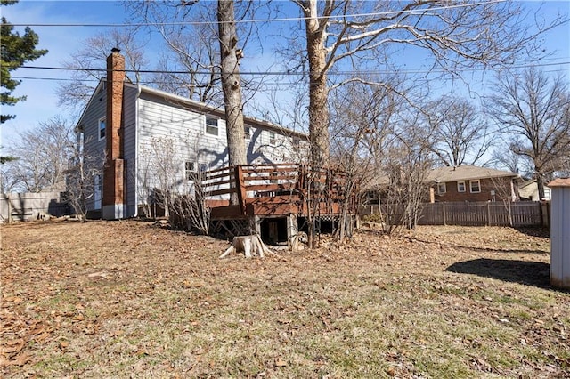 back of property featuring a deck, a chimney, and fence