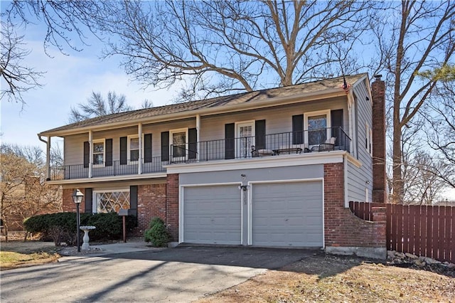 view of front facade with driveway, a chimney, an attached garage, fence, and brick siding