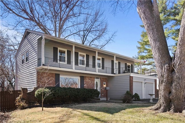 view of front of property featuring an attached garage, a balcony, brick siding, fence, and a front yard