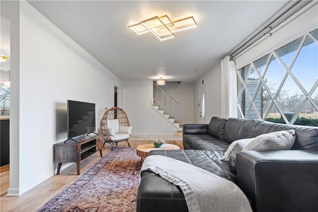 living area with light wood-style floors, baseboards, and stairway