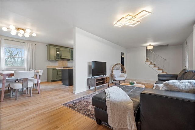 living room with light wood-style flooring, baseboards, and stairs