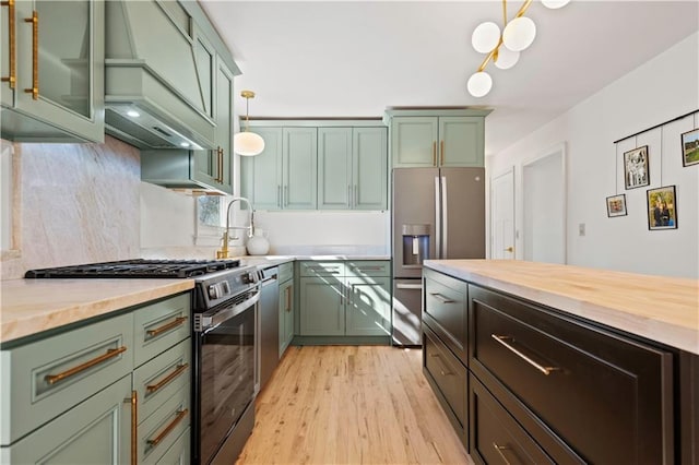 kitchen featuring light wood-style floors, custom range hood, stainless steel appliances, and green cabinetry