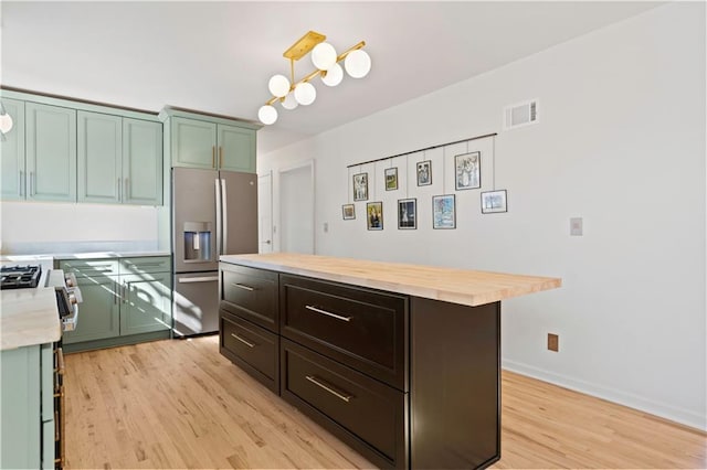 kitchen with wooden counters, appliances with stainless steel finishes, light wood-type flooring, green cabinetry, and baseboards