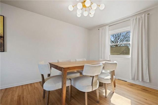 dining room featuring a notable chandelier, light wood-style flooring, and baseboards