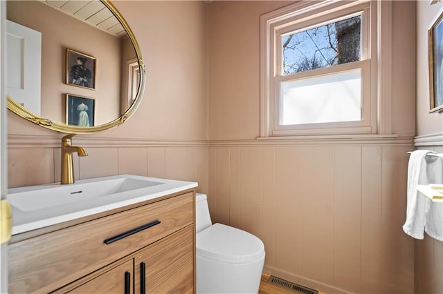 bathroom with wainscoting, visible vents, vanity, and toilet