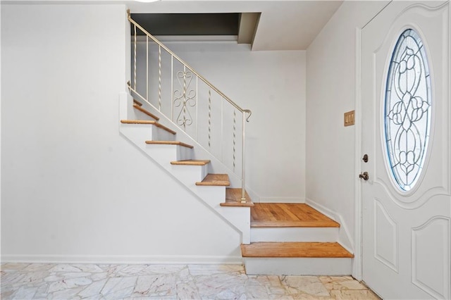 entryway featuring marble finish floor, stairs, and baseboards