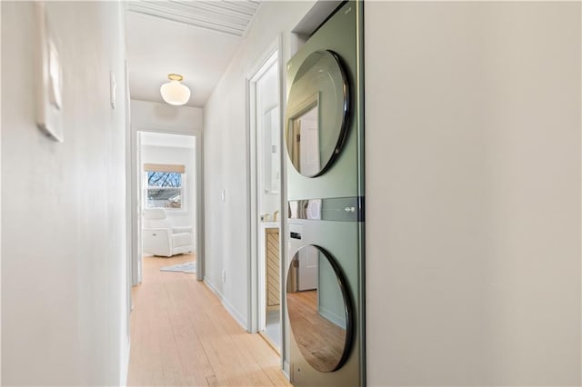 hallway with stacked washer and dryer and light wood-style flooring