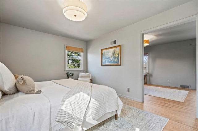 bedroom with visible vents, baseboards, and wood finished floors