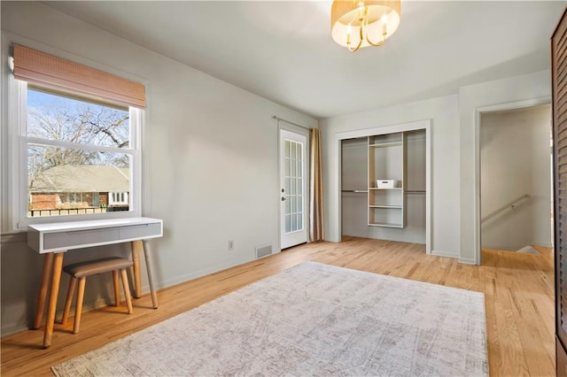 interior space featuring an inviting chandelier, baseboards, visible vents, and wood finished floors