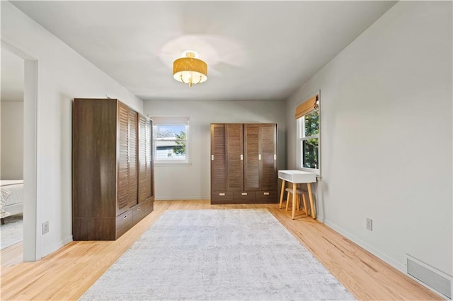 bedroom with wood finished floors, visible vents, and baseboards