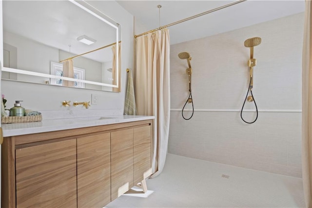 bathroom with a tile shower and vanity