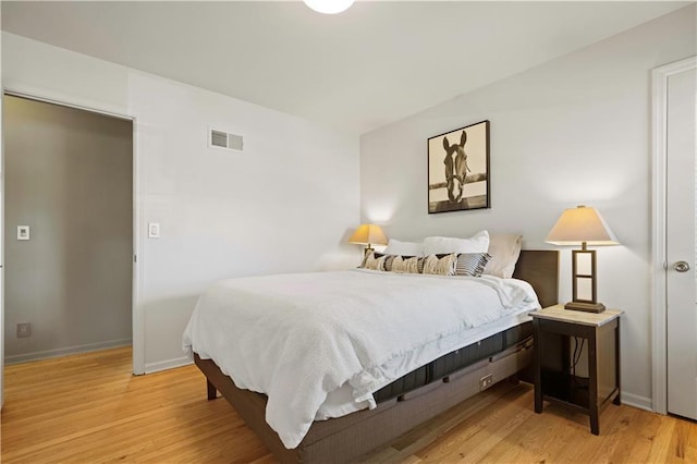 bedroom with baseboards, visible vents, and wood finished floors