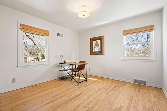 office with light wood finished floors, visible vents, and a healthy amount of sunlight