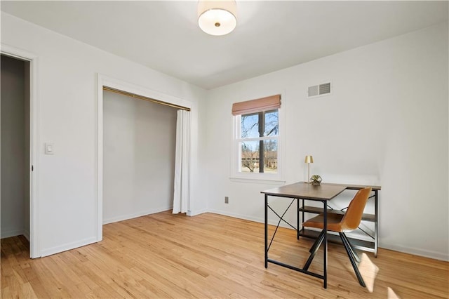 office space with light wood-type flooring, visible vents, and baseboards