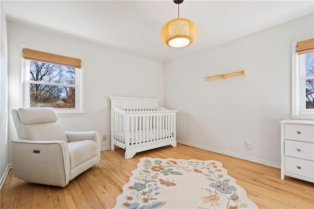 bedroom with a nursery area, wood finished floors, and baseboards