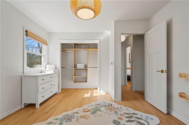 bedroom featuring light wood-type flooring, baseboards, and a closet