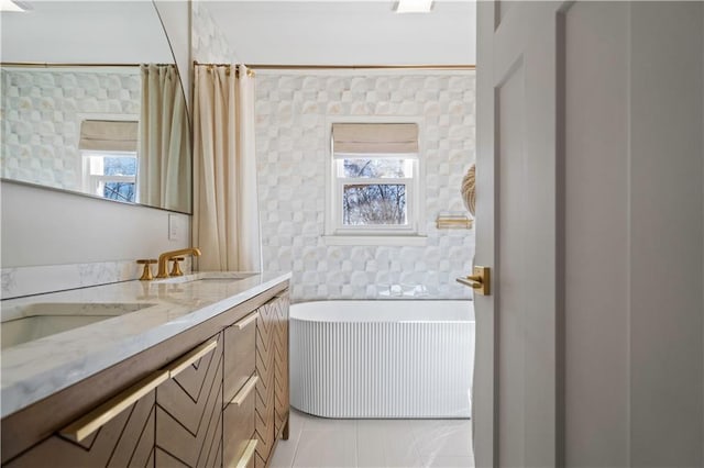 full bathroom featuring double vanity, a sink, a bath, and tile patterned floors