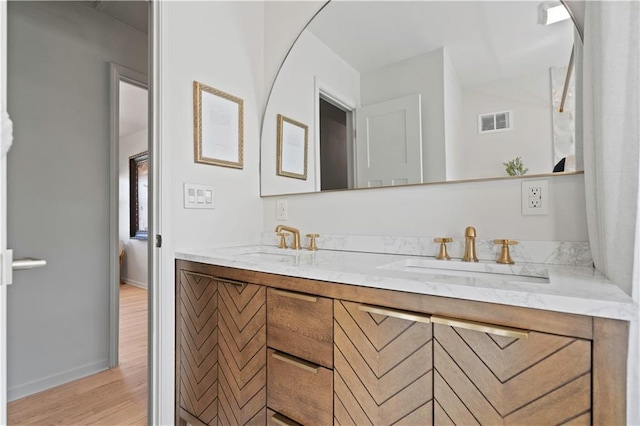 full bath featuring double vanity, wood finished floors, a sink, and visible vents