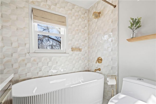 bathroom featuring toilet, a freestanding tub, tile walls, and vanity