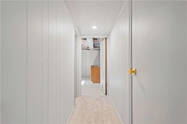 hall with a textured ceiling and light colored carpet