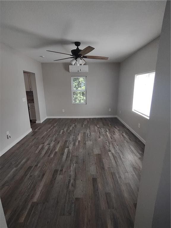 unfurnished room with a ceiling fan, baseboards, and dark wood-type flooring