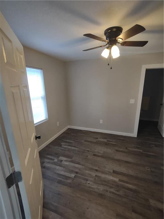 empty room with dark wood-type flooring, ceiling fan, and baseboards