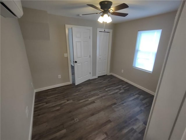 unfurnished bedroom with a ceiling fan, baseboards, dark wood-type flooring, and an AC wall unit