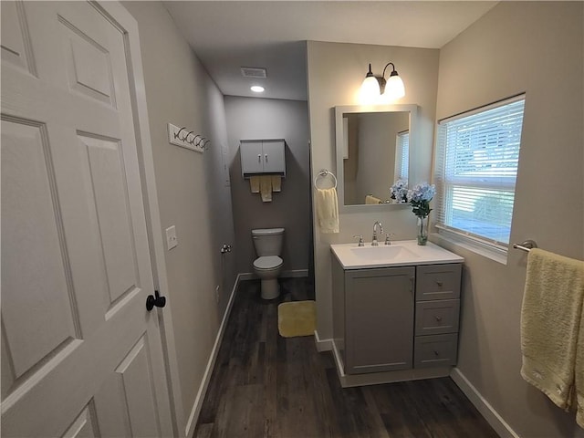 bathroom with visible vents, toilet, vanity, wood finished floors, and baseboards