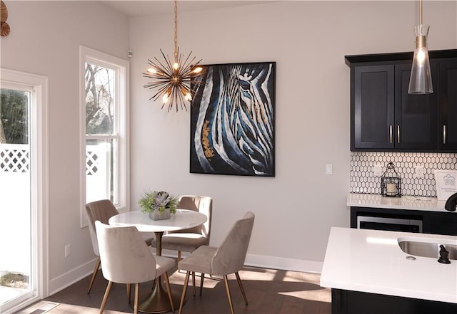 dining space featuring a chandelier, dark wood-style floors, and baseboards