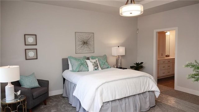 bedroom with dark carpet, ensuite bath, and baseboards